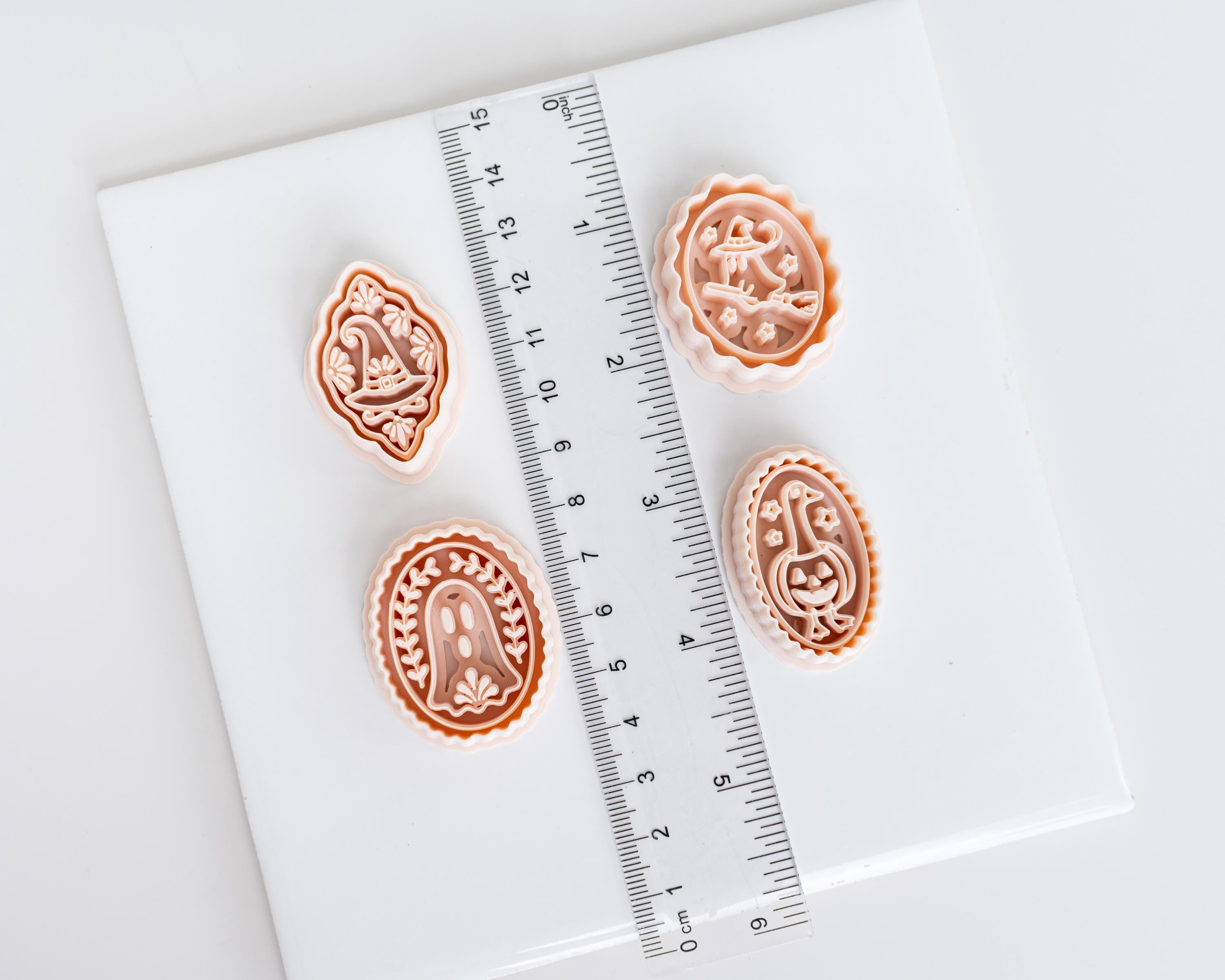four decorative cookie cutters of various shapes and sizes, placed on a white surface next to a ruler for size comparison.
