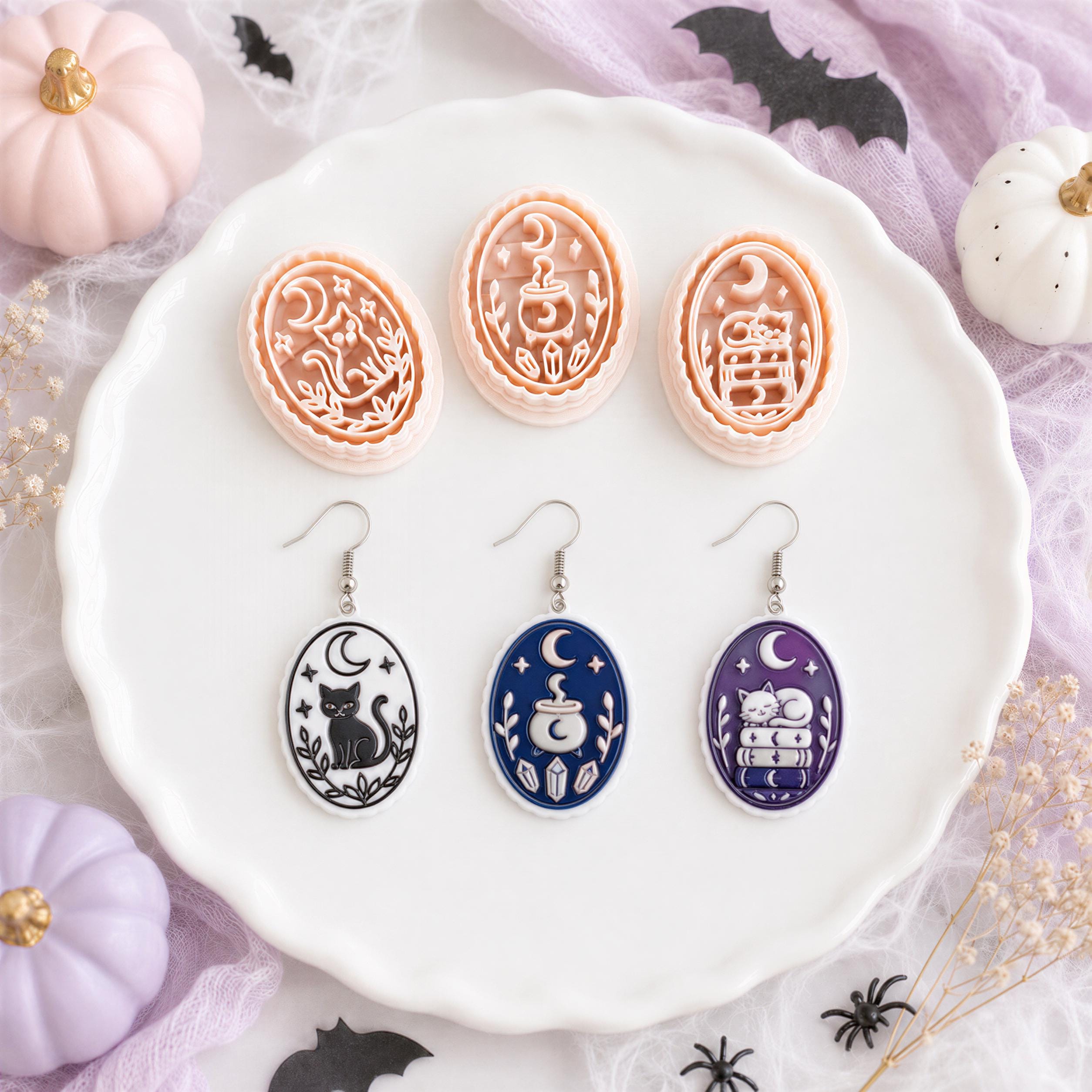 Halloween clay cutter set with finished black, navy and purple earrings featuring a cat, crescent moon, cauldron and cat on stacked books.