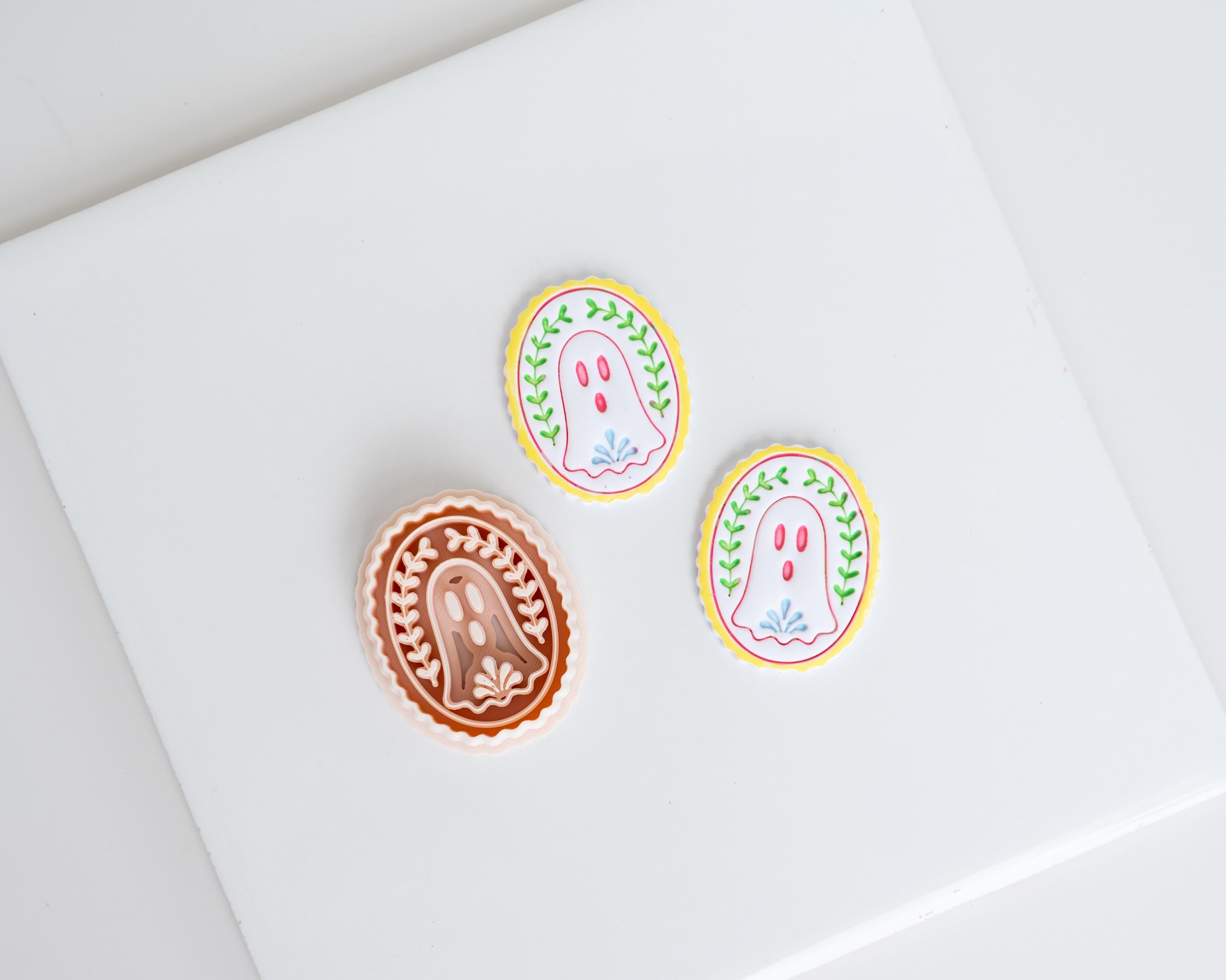 three circular or oval-shaped cookies with different designs and colors, placed on a white surface.