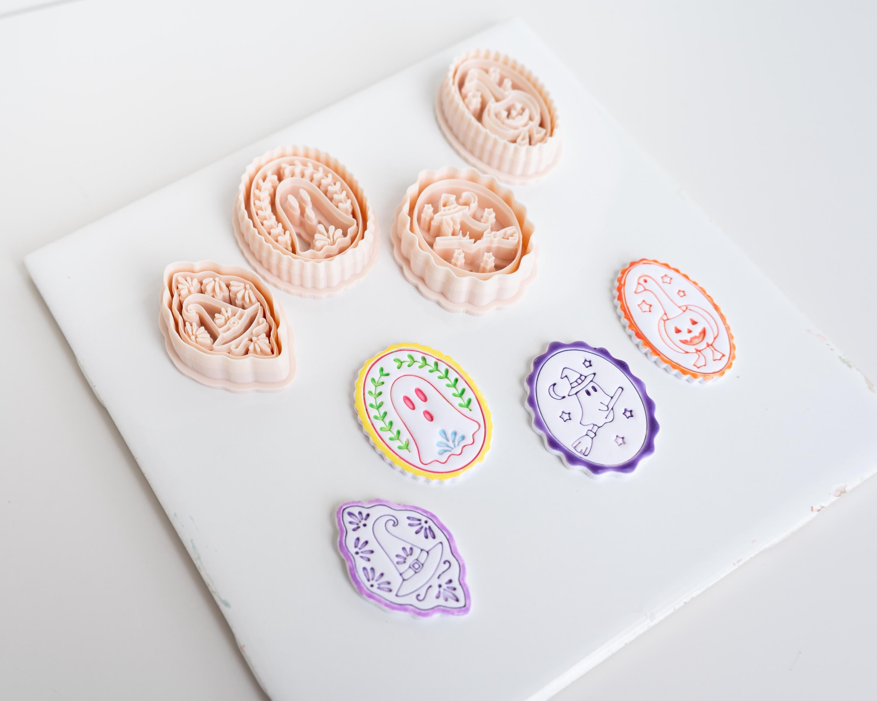 a collection of seven cookie cutters with various shapes and designs, including a ghost, a pumpkin, and other festive or decorative elements.