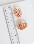 Halloween clay cutters shown beside a ruler for scale, featuring a cauldron and crescent moon design and a cat resting on stacked books.