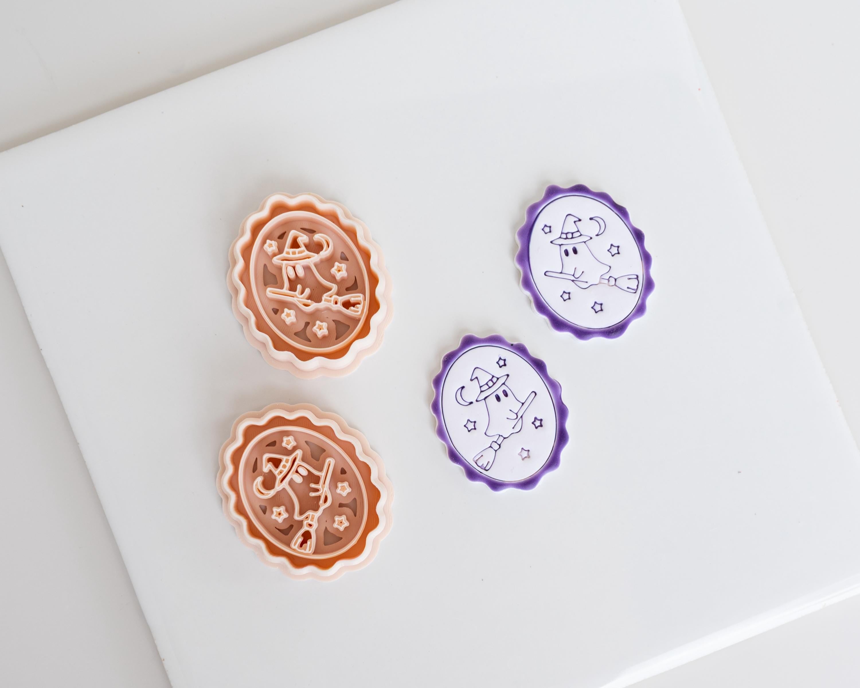 two cookie cutters, one orange and one purple, placed on a white surface.