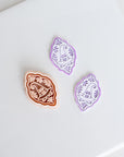 three decorative objects, including a brown and white patterned object, a purple and white patterned object, and a white object with a purple and white pattern.